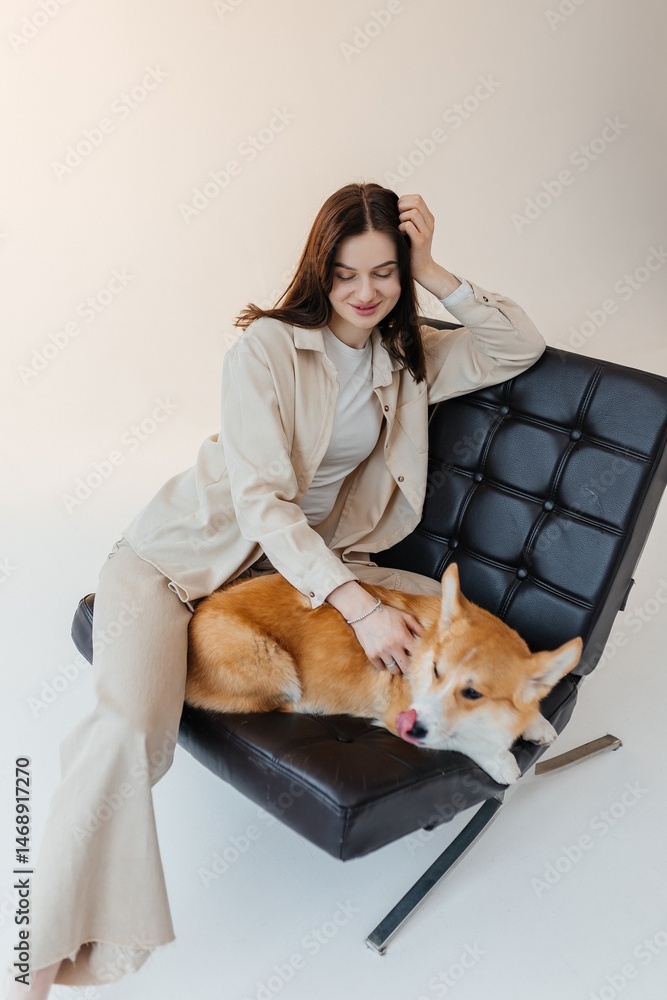 Young woman playing with her corgi dog. Healthy lifestyle and living in an apartment with a pet. Pets concept.