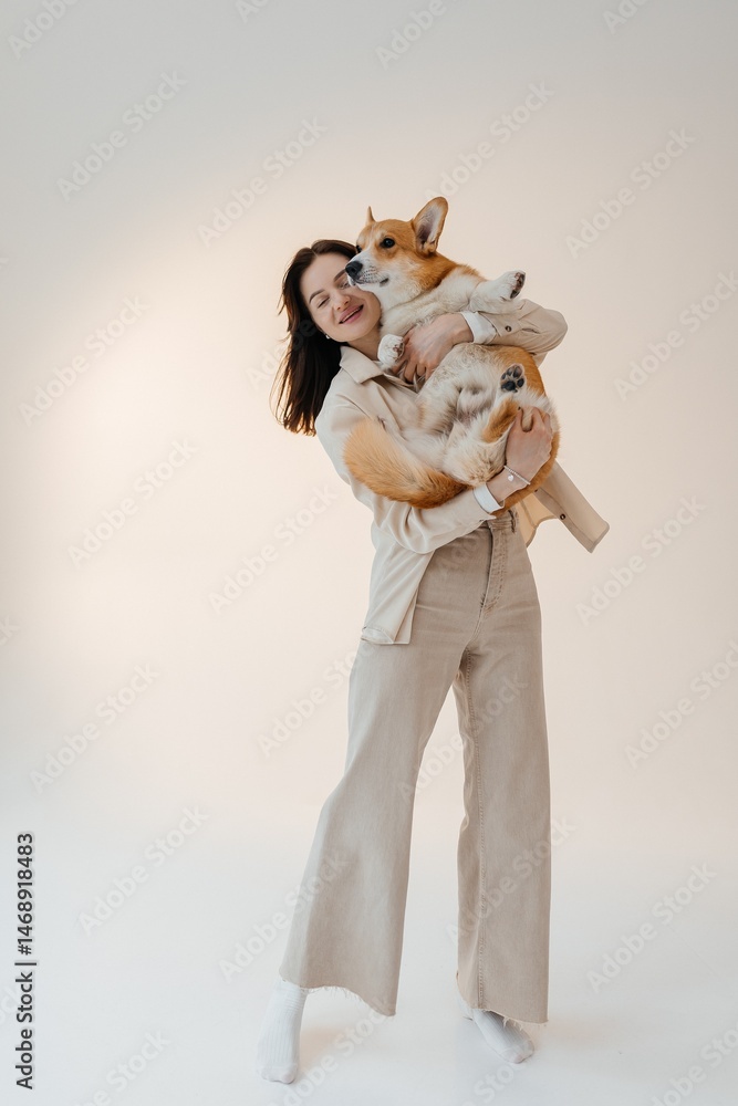 Young woman playing with her corgi dog. Healthy lifestyle and living in an apartment with a pet. Pets concept.