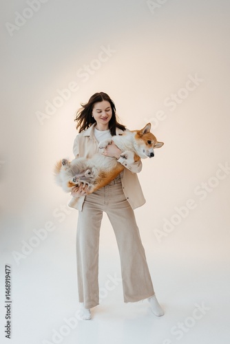 Young woman playing with her corgi dog. Healthy lifestyle and living in an apartment with a pet. Pets concept.