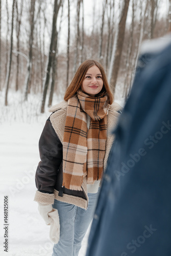 Obraz na płótnie A couple in love on a walk in a snowy winter park. A walk in the winter forest of two happy people. A guy and a girl holding hands and hugging. w salonie