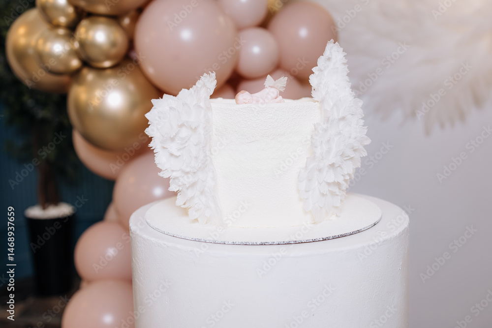 White cake for celebrating a child's baptism. Sweet cake with white wings. Photo zone for a child's baptism.