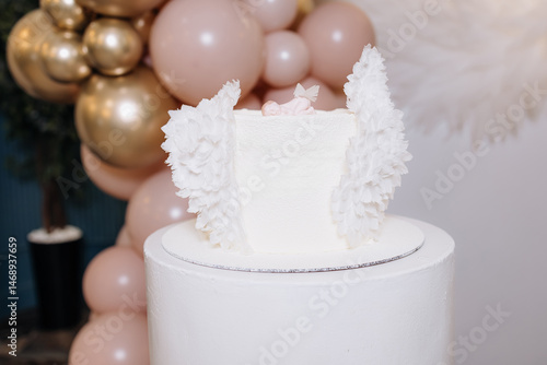Obraz na płótnie White cake for celebrating a child's baptism. Sweet cake with white wings. Photo zone for a child's baptism. w salonie