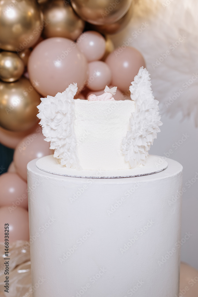 White cake for celebrating a child's baptism. Sweet cake with white wings. Photo zone for a child's baptism.