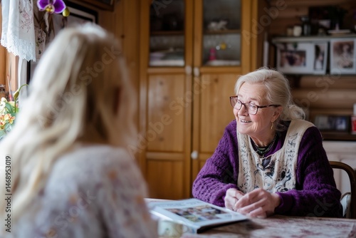 A young woman reads a book to an older woman, who listens attentively