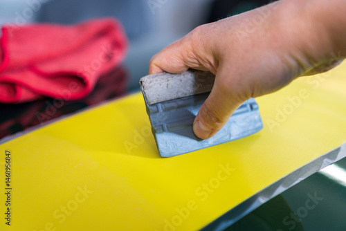 Obraz na płótnie Close-up of a person's hand installing a vinyl wrap on a car