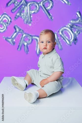 Obraz na płótnie Birthday of a 1 year old boy. A small one year old boy in a t-shirt runs and laughs around the room. A toddler boy is happy and smiling. w salonie