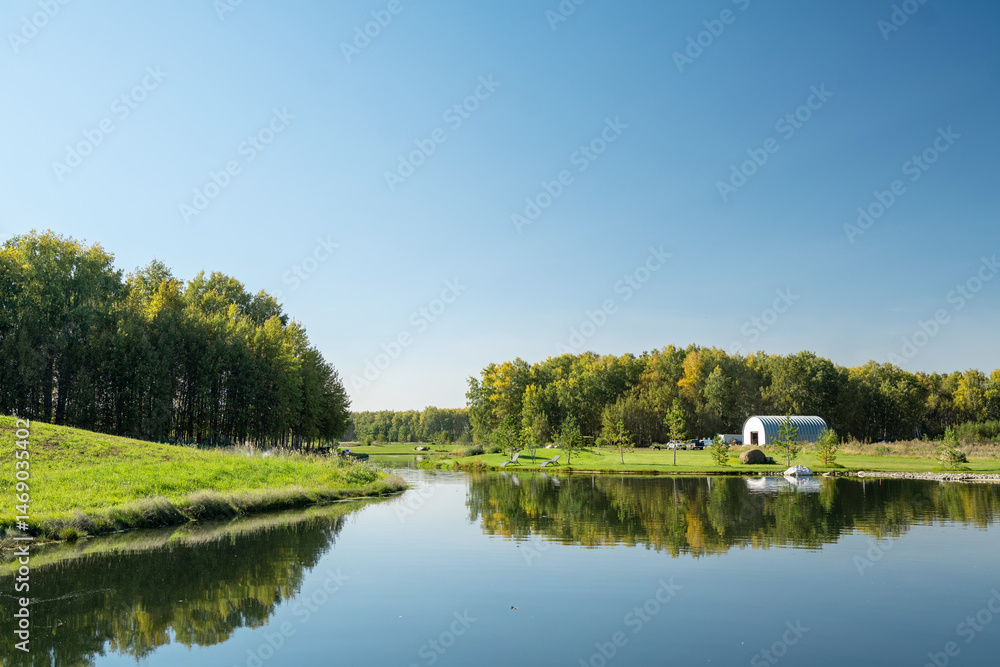 Fototapeta premium A serene and tranquil pond featuring a beautiful fountain amidst a lush green landscape