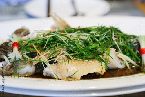 Steamed fish Cantonese style Chinese cuisine dish with scallion and shredded ginger closeup view