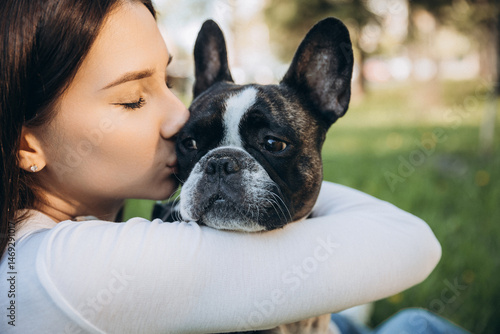 girl holding french bulldog in her arms. girl kissing and having fun with her dog