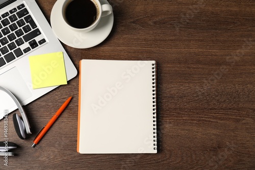 Notebook, sticky note, pen, headphones, coffee and laptop on wooden table, flat lay. Space for text