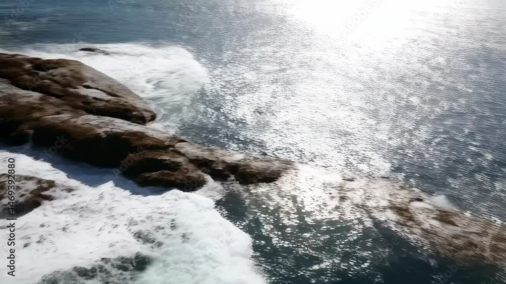 Ocean waves crashing over coastal rocks with blue sea water, creating white foam against a sunny horizon, showing natural coastal beauty Ocean waves crashing over coastal rocks with blue sea water, creating white foam against a sunny horizon, showing natural coastal beauty