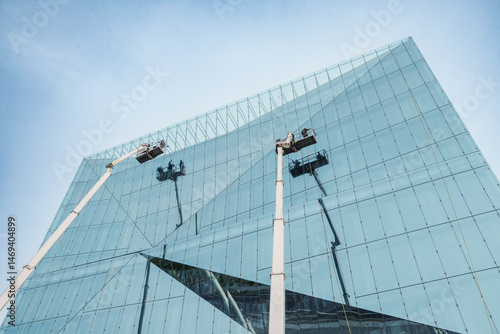 Cleaner worker using a cherry picker to clean a glas facade of a contemporary office building