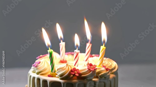 Birthday cake with flaming candles and flowers on gray background with copy space