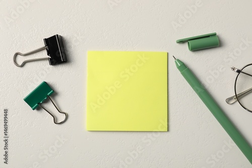 Sticky note, pen and binder clips on white table, flat lay