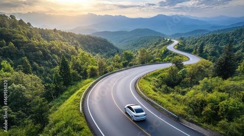 Scenic winding road through lush mountains with car under the sunrise light