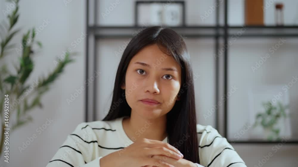 Young asian woman talking seriously and explaining a work-related issue during an online meeting or remote consultation, sitting at desk in home office environment. Young asian woman talking seriously and explaining a work-related issue during an online meeting or remote consultation, sitting at desk in home office environment.