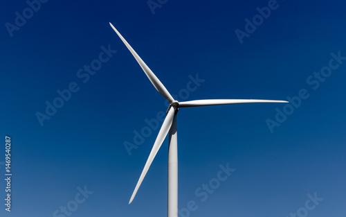 White, three-bladed wind turbine against a dark blue sky