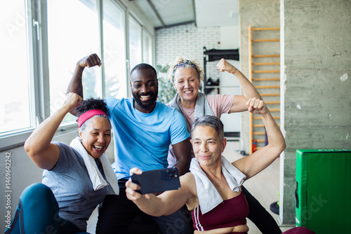 Diverse group of happy seniors and fitness trainer taking a post-workout selfie at the gym