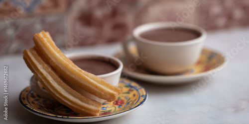Churros rest on cups of hot chocolate in cozy Spanish style cafe