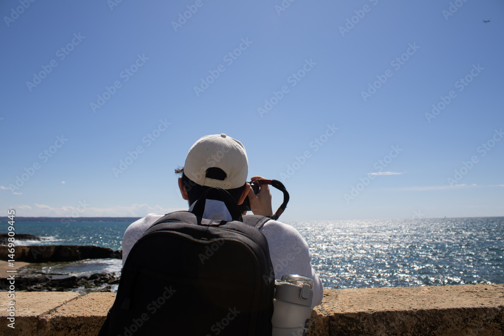 Fototapeta premium Young man photographing the Mediterranean Sea horizon on a sunny day, outdoor photography