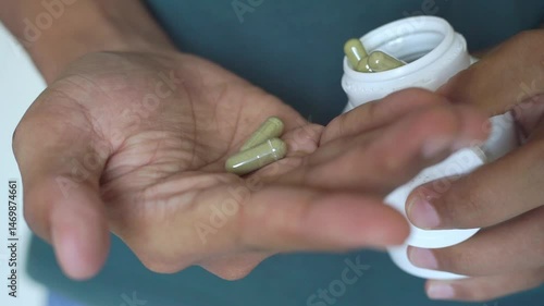 Male hand pouring green medicine capsules from plastic bottle into a palm, antibiotic pills, vitamins, painkillers, isolated on transparent background. healthcare and treatment concept