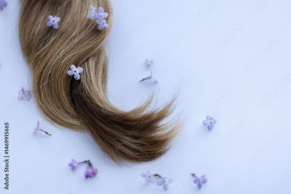 Naklejka premium Female long hair with lilac flowers. Closeup.