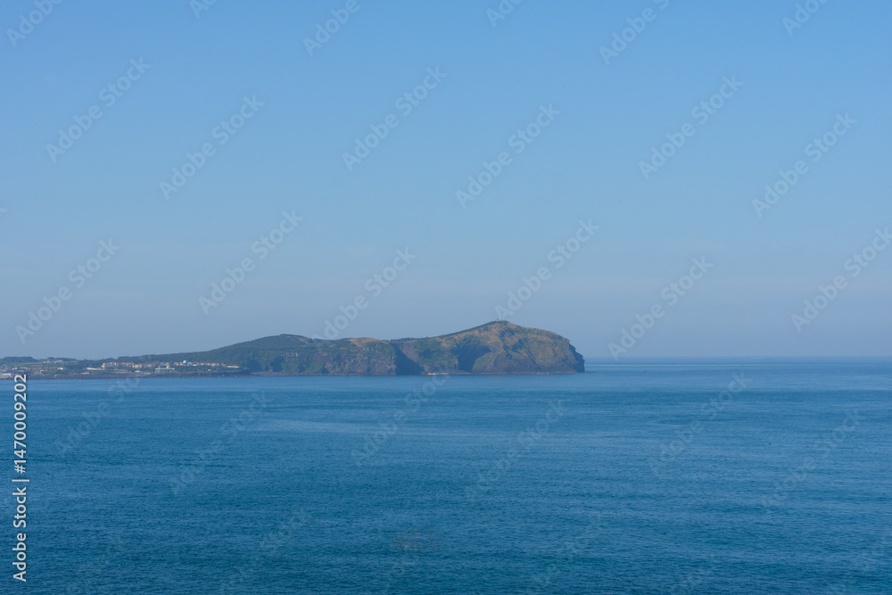 Fototapeta premium Seongsan Ilchulbong volcanic tuff cone panoramic view, calm mood, representing Jeju, South Korea, with blue sky and ocean