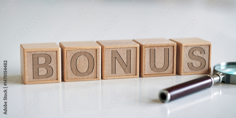 Fototapeta premium Wooden blocks spelling BONUS, next to magnifying glass on white background, showcasing business concept, reward, or incentive