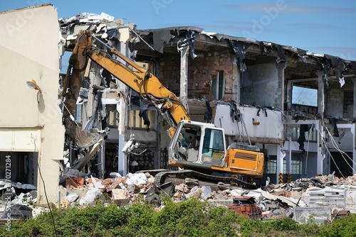 A yellow crane demolishing an old house
