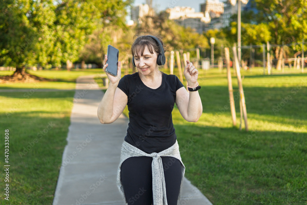 Obraz premium Musical escape: Mature woman dancing outdoors, lost in her music