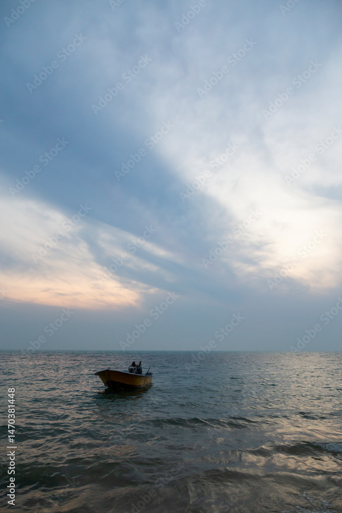Obraz premium A serene sunset voyage: two souls share a peaceful moment aboard a small boat, adrift on gentle waters under soft, shifting skies.