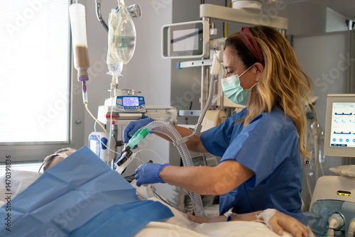 Doctor attending patient lying in hospital bed with respiratory problems