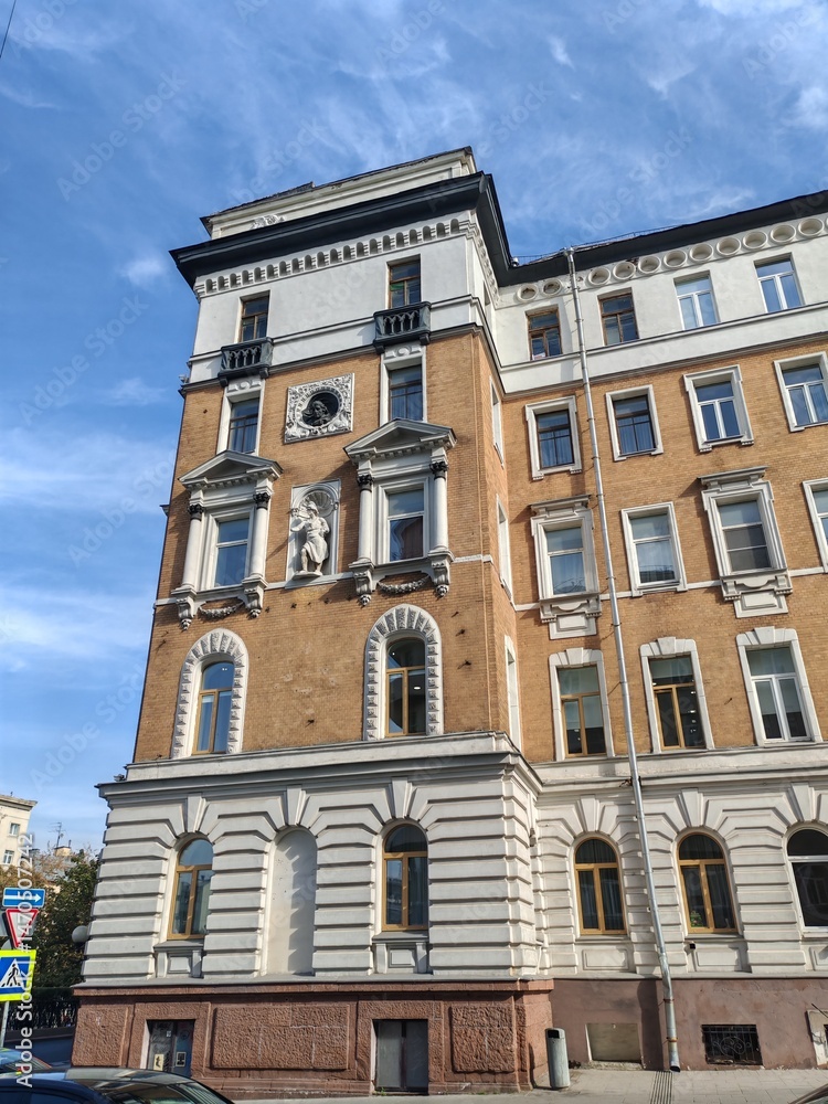 Obraz premium An old European-style building showcasing intricate stonework, arched windows, and a detailed sculptural element. This image symbolizes forgotten grandeur in urban landscapes.