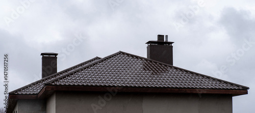 Fotografie Wet brown metal roof with two chimneys