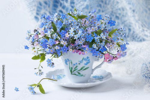 Bouquet of spring flowers forget-me-nots and omphalodes close-up in a cup on the table , blur, beautiful card