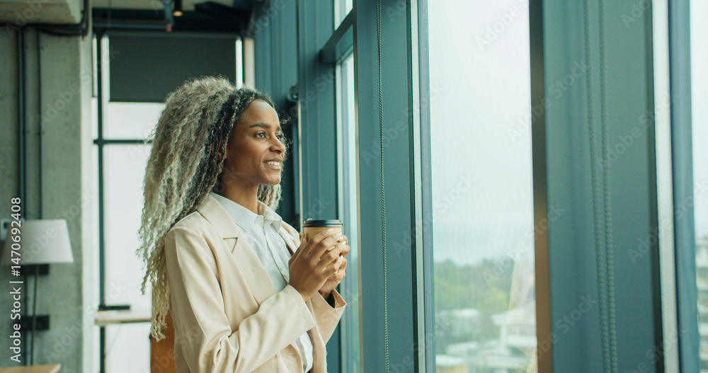 Fototapeta premium Businesswoman holding coffee while looking outside