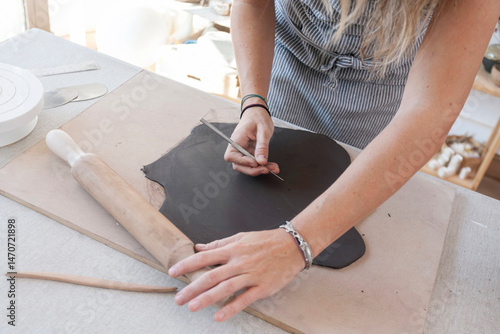 Close-up of female hands shaping wet clay in a pottery studio