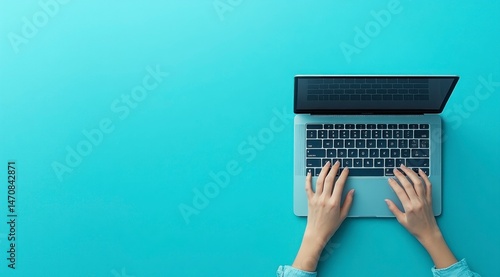 Hands typing on a laptop, teal background