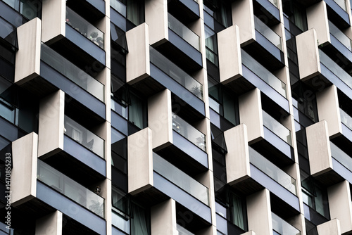 Layered geometric facade of modern building with alternating white and dark elements, creating rhythm, pattern and structural contrast through architectural repetition.