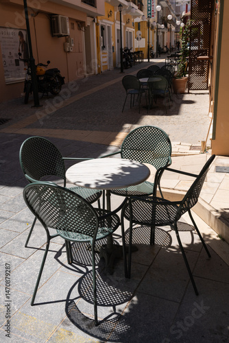 Cafe Table in Narrow Greek Alley. Metal cafe table and chairs sit in the shade of a quiet alleyway in Zakynthos, Greece.