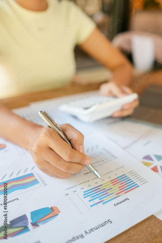 Close-up of a woman reviewing financial charts with a pen and calculator, focusing on data analysis and business strategy. Close-up of a woman reviewing financial charts with a pen and calculator, focusing on data analysis and business strategy.