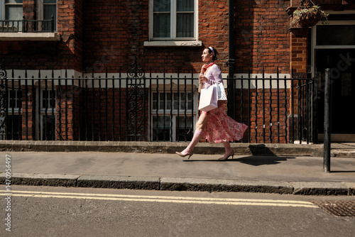 Photography Elegant shopper walking on london sidewalk after successful shopping spree