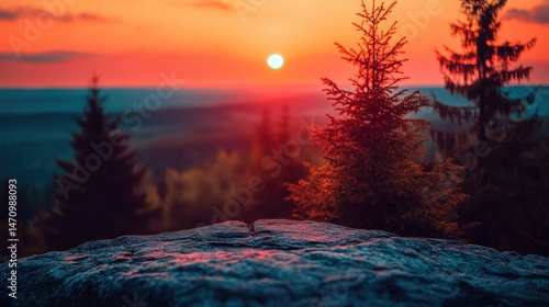 Majestic sunset over a mountain peak.  Rocky outcrop foreground, pine trees in the background