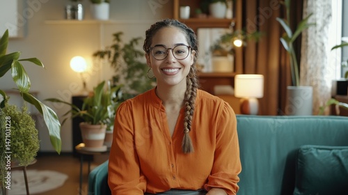 Wallpaper Mural Smiling Young Woman in Orange Shirt with Braided Hair and Glasses Sitting on Green Sofa Torontodigital.ca