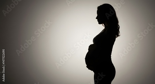 Pregnant Woman Silhouette Embracing Her Belly in Studio
