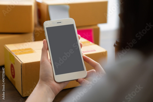 Hand holding smartphone with a blank screen on table, for putting advertising to promote.
