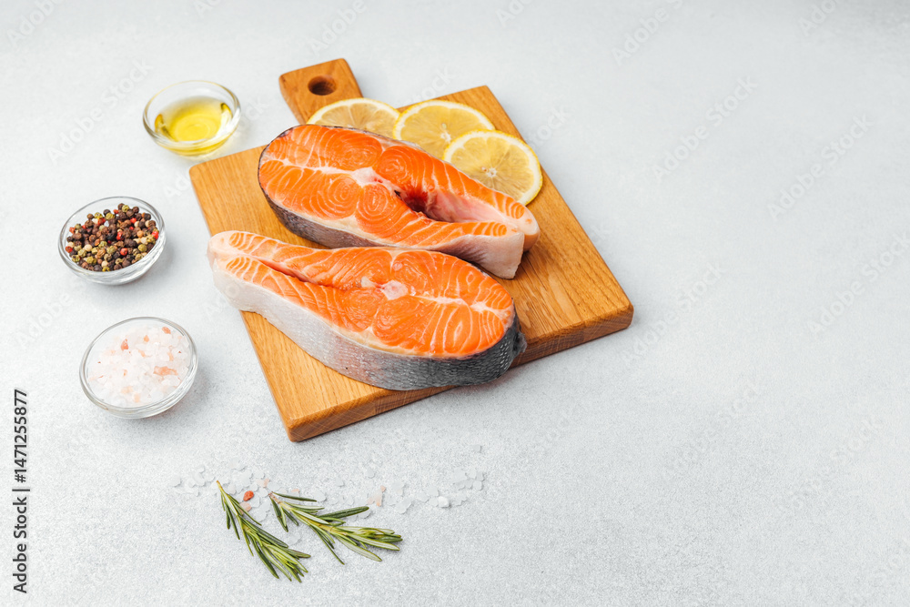 Fresh salmon fillets ready for cooking with lemon and spices on a wooden board
