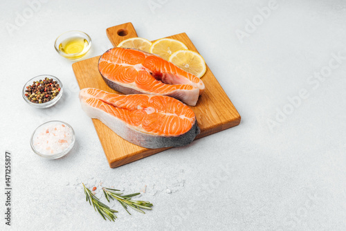 Obraz na płótnie Fresh salmon fillets ready for cooking with lemon and spices on a wooden board w salonie