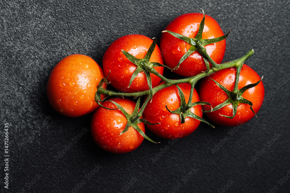 Fresh red tomatoes with water droplets on a dark surface ready for cooking