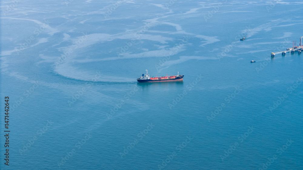 Naklejka premium Aerial view of an LPG tanker ship navigating calm blue waters near an offshore terminal. Ideal for themes on energy transport, maritime industry, and international gas shipping.